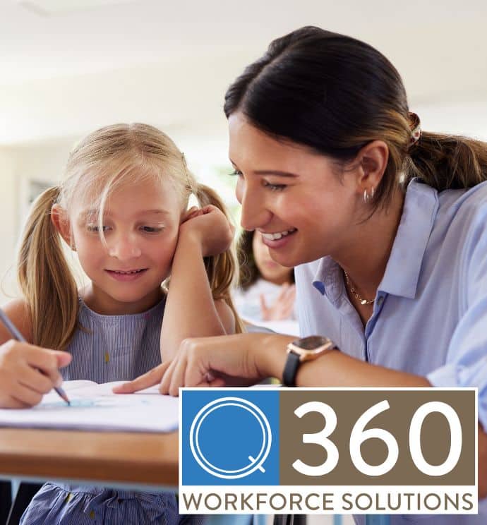 Brunette teacher knelt down helping a blonde student with pigtails