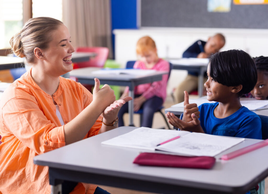 Using sign language, female teacher and boy engaging in communication at school