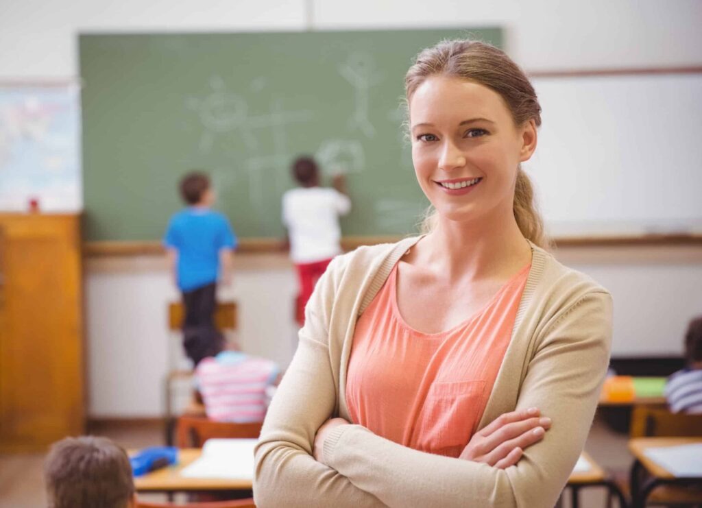Pretty teacher smiling at camera at back of classroom