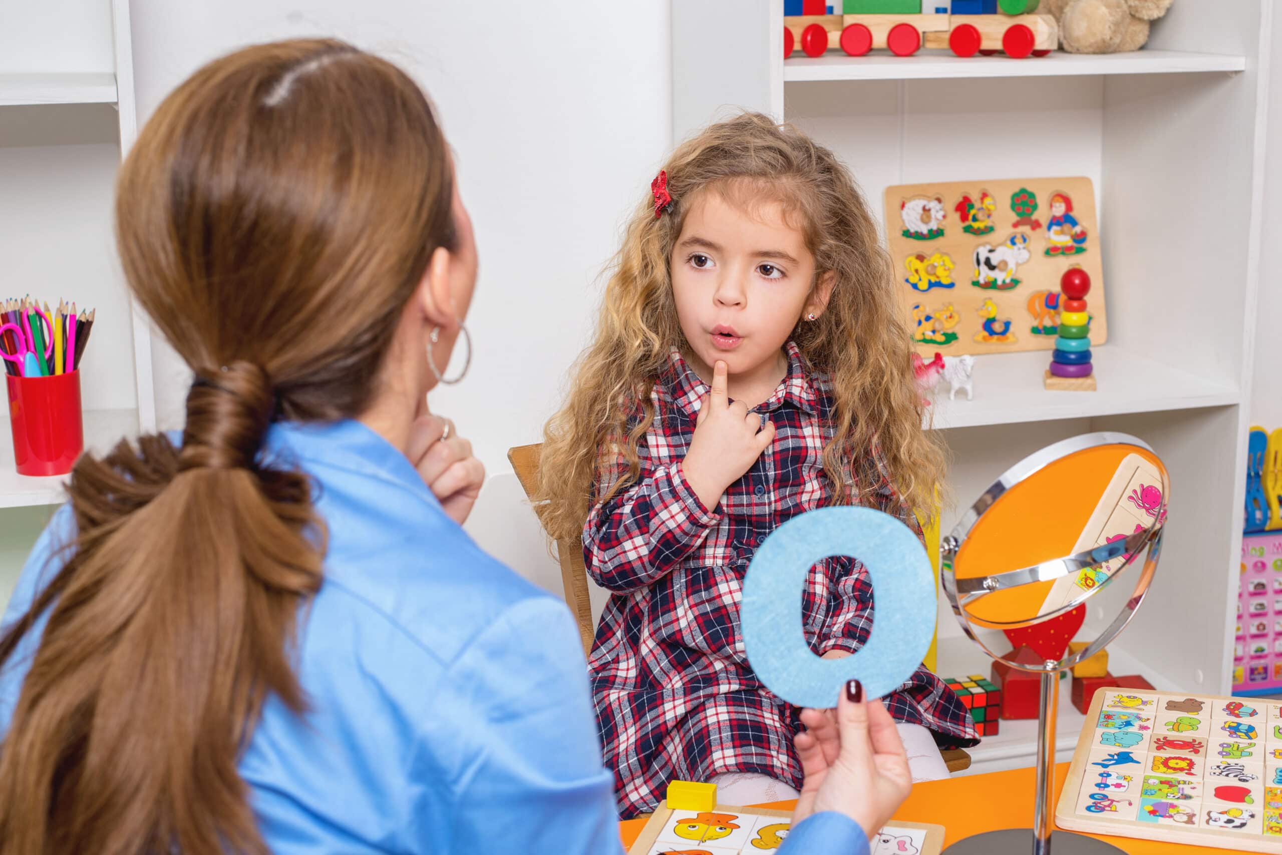 Preschooler exercising correct pronunciation with speech therapist.