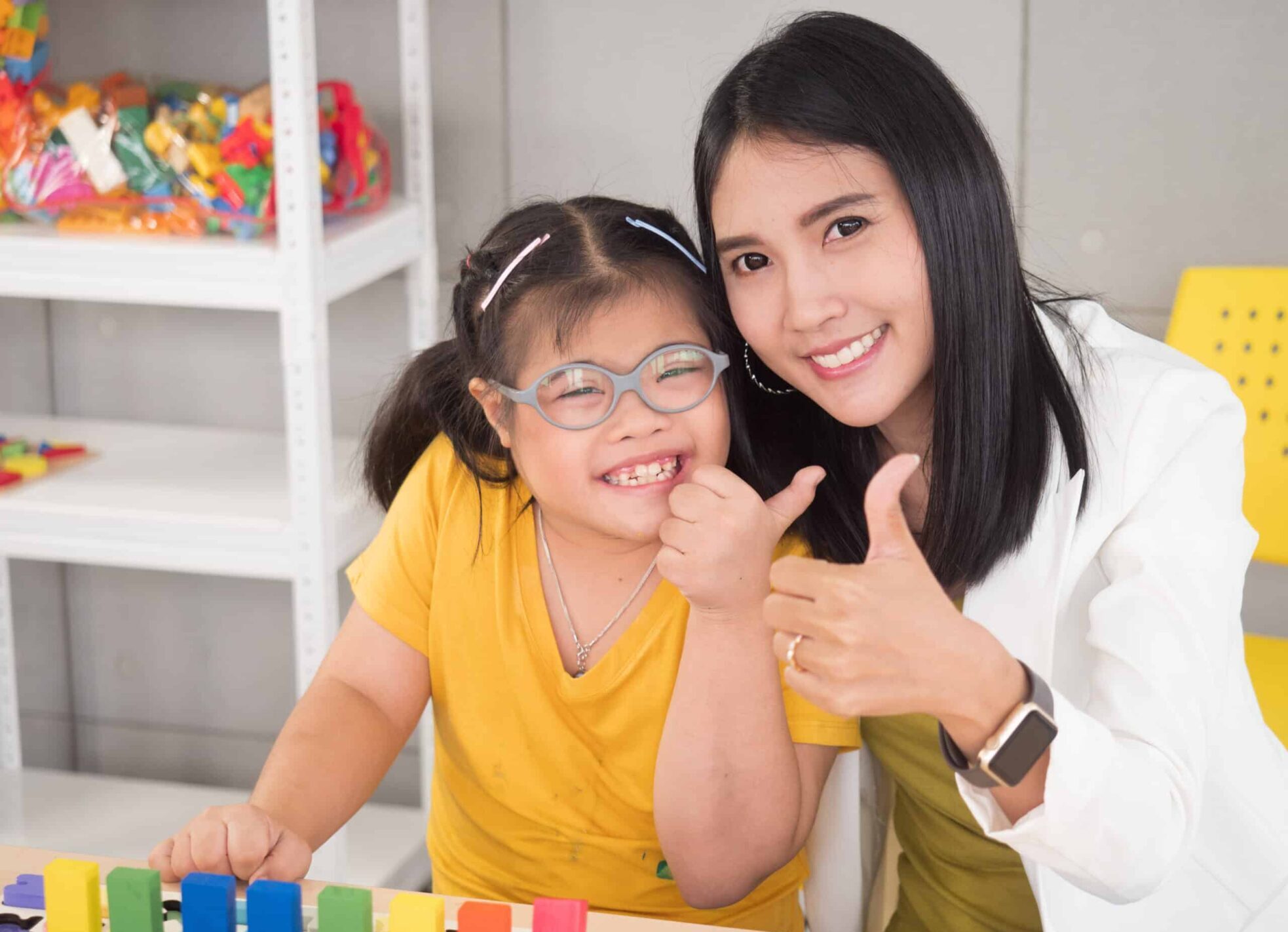 Special education professional giving a thumbs up with a student