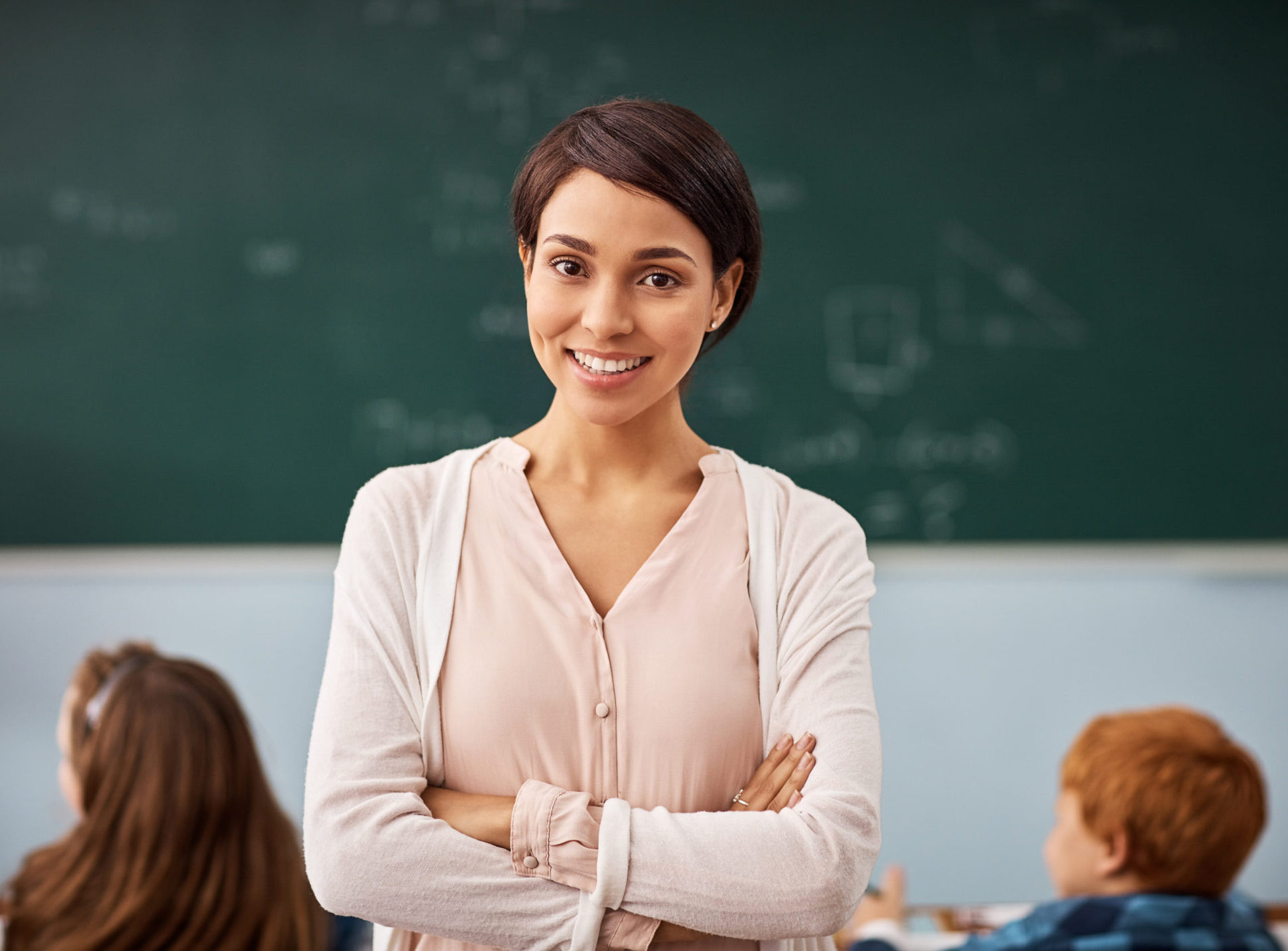 Portrait of a young female teacher standing in a classroom.
