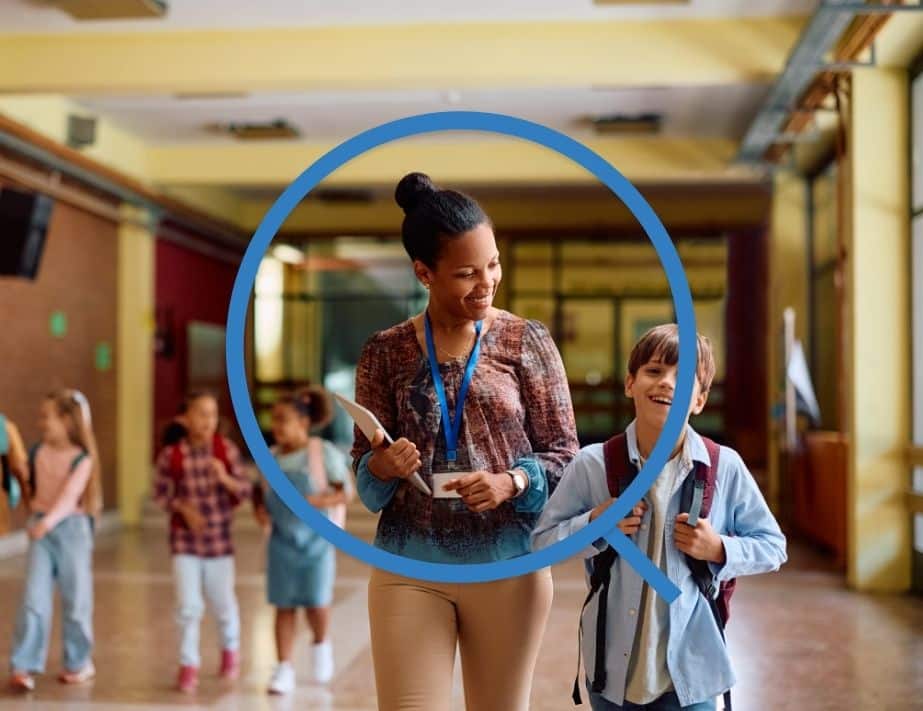Happy teacher and elementary student walking through hallway.