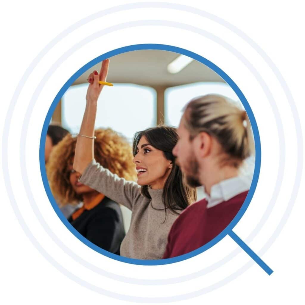 Woman raising her hand amongst a group of peers during a professional development session