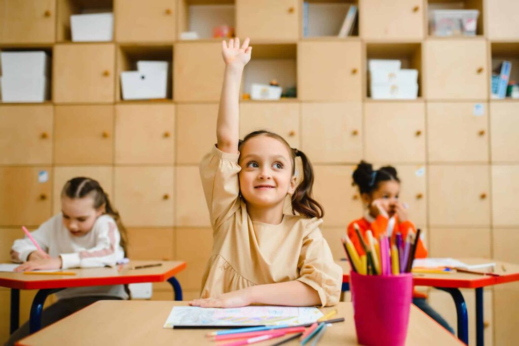 Young student raising her hand in class