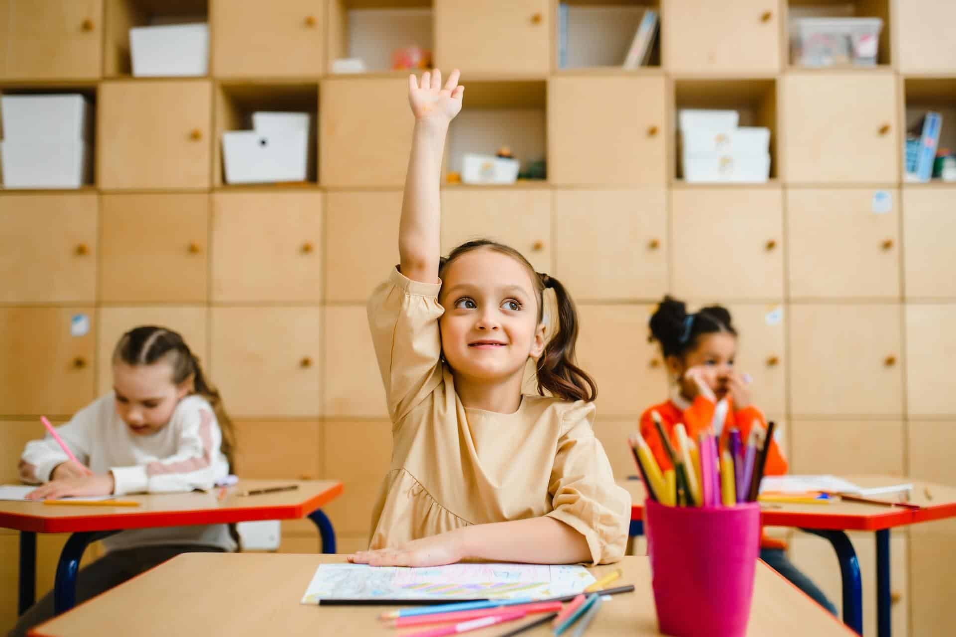 Young student raising her hand in class