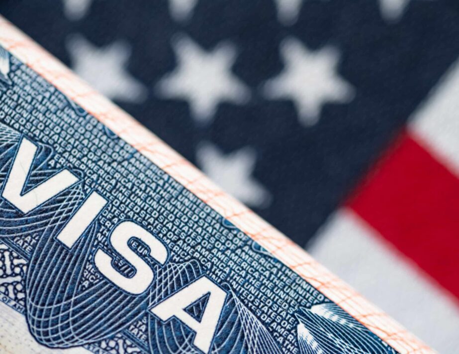 Visa overlaying the United States flag signifying the approval of an E-3 Visa to work in the U.S.