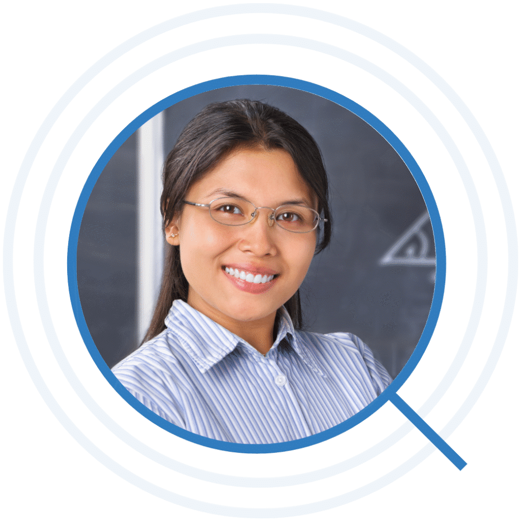 Professional headshot of a woman wearing glasses and standing in front of a classroom chalkboard, representing an E-3 visa teacher or education professional.