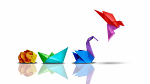 Four stages of origami paper transforming from a crumpled ball into a paper boat, a swan, and finally a flying bird, symbolizing growth and development.
