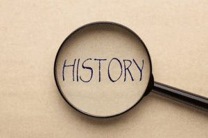 Magnifying glass focusing on the word 'HISTORY' written in bold letters on a beige background.