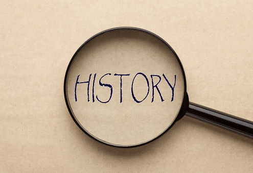 Magnifying glass focusing on the word 'HISTORY' written in bold letters on a beige background.